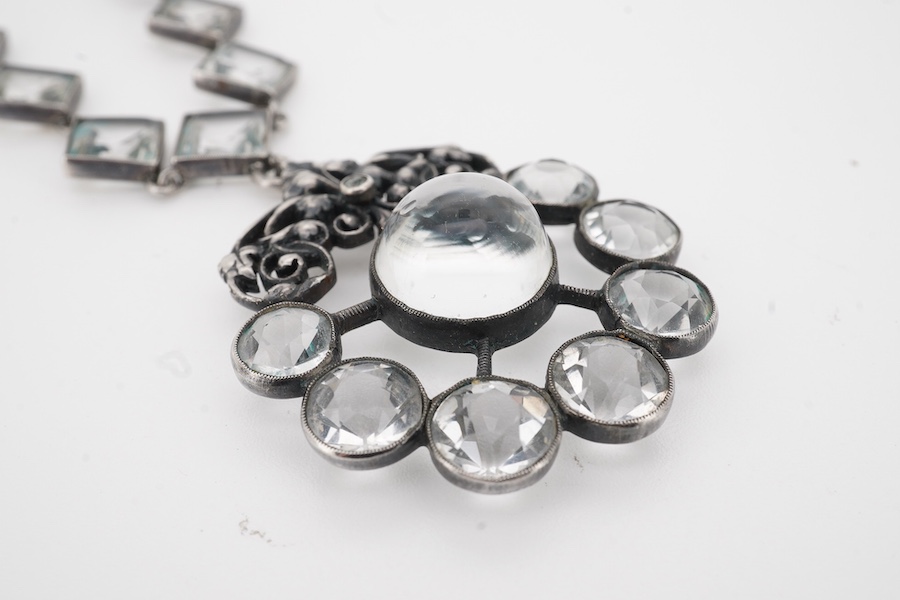 An Arts & Crafts white metal and paste cluster set circular pendant, diameter 33mm, hung from an associated white metal and quartz set necklace, 37cm.